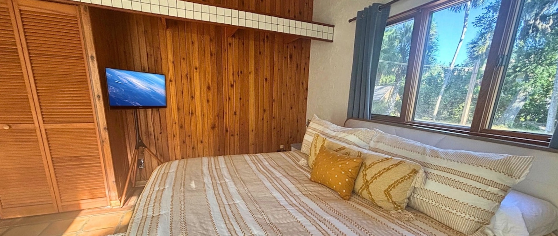 King suite with wall-mounted smart TV and treetop views